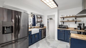Eine moderne Küche mit Edelstahlgeräten, blauen Schränken und einer Holzarbeitsplatte.