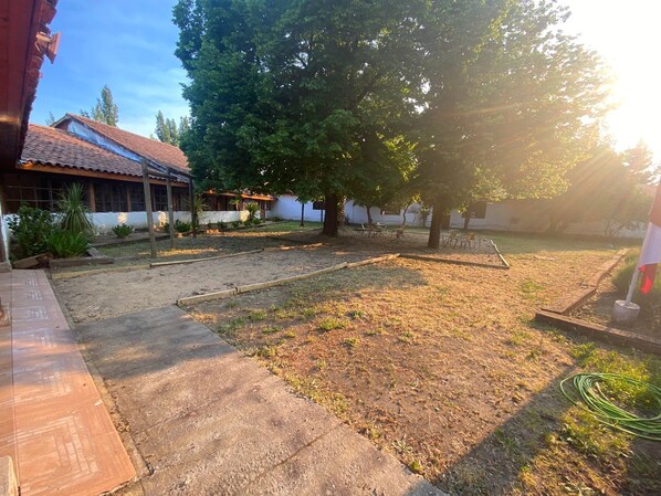 A courtyard with a paved walkway, a grassy area, and a building with a tiled roof.