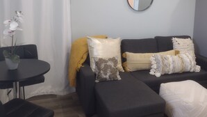 A modern living room with a grey sofa, a round mirror, and a small table with a potted plant. - Private, Quiet 1 Bedroom in Amityville (Amityville)
