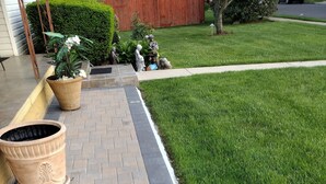 A paved pathway with potted plants on the left, leading to a well-maintained lawn. - Private, Quiet 1 Bedroom in Amityville (Amityville)