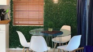 A dining area with a glass table, white chairs, and a green wall. - Manatee Pocket! 1 Bedroom, 1 Bath Unit To Yourself (Stuart)