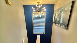 Un escalier avec un luminaire au-dessus et un tableau encadré accroché au mur.
