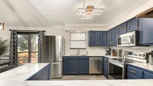 Une cuisine moderne avec des meubles bleu foncé, des appareils en acier inoxydable et un plan de travail en marbre.