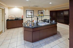 A kitchen area with a central island, a sink, and a countertop with various appliances and utensils. - Cozy Suite | Free Breakfast + Pool (Plainfield)
