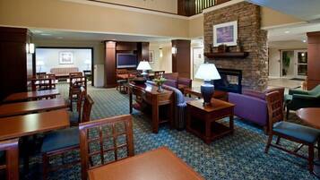 A hotel lobby with a fireplace, seating area, and a television.