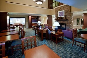 A hotel lobby with a fireplace, seating area, and a television. - Cozy Suite | Free Breakfast + Pool (Plainfield)