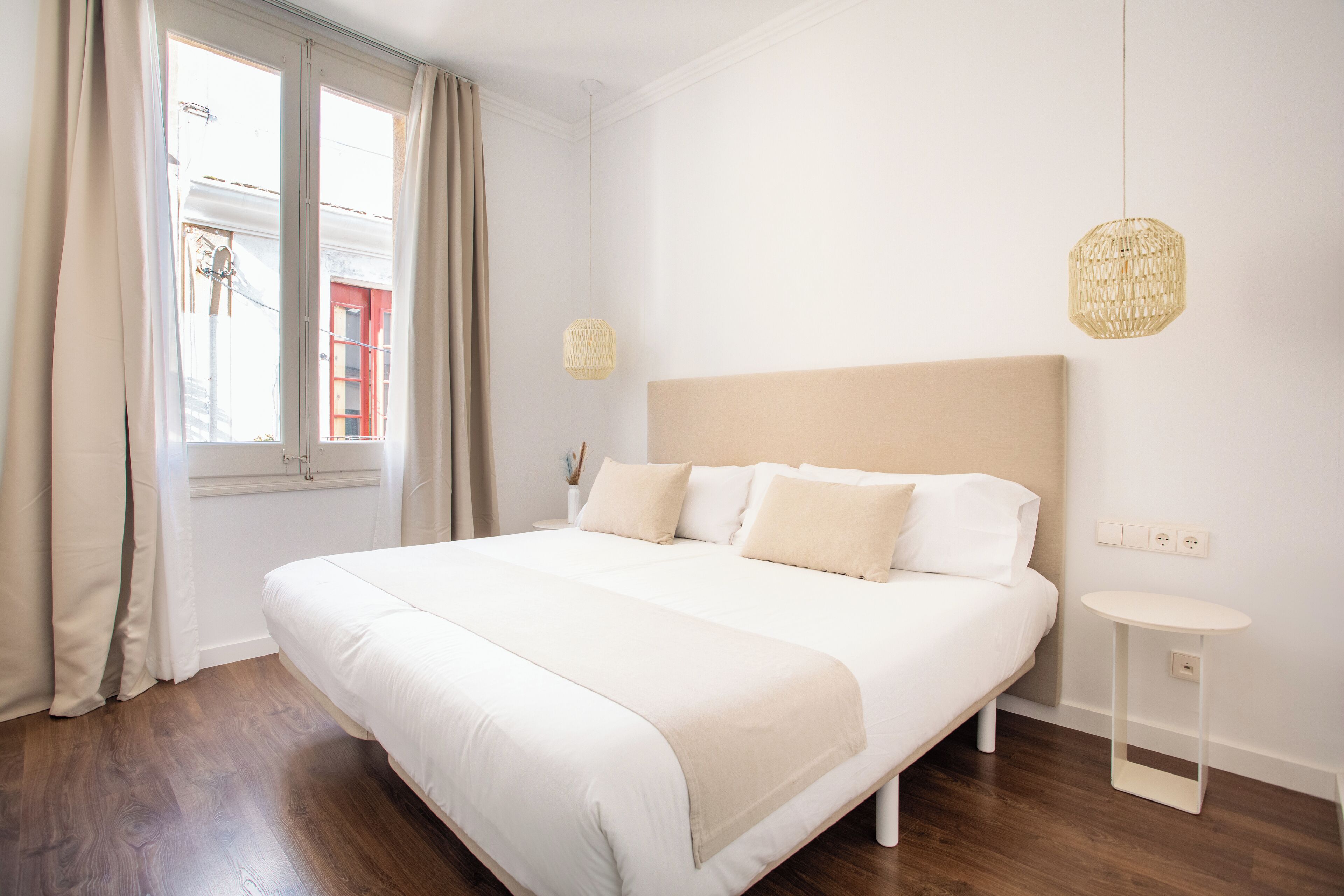 A neatly arranged bedroom with a large bed, a bedside table, and a hanging light fixture.