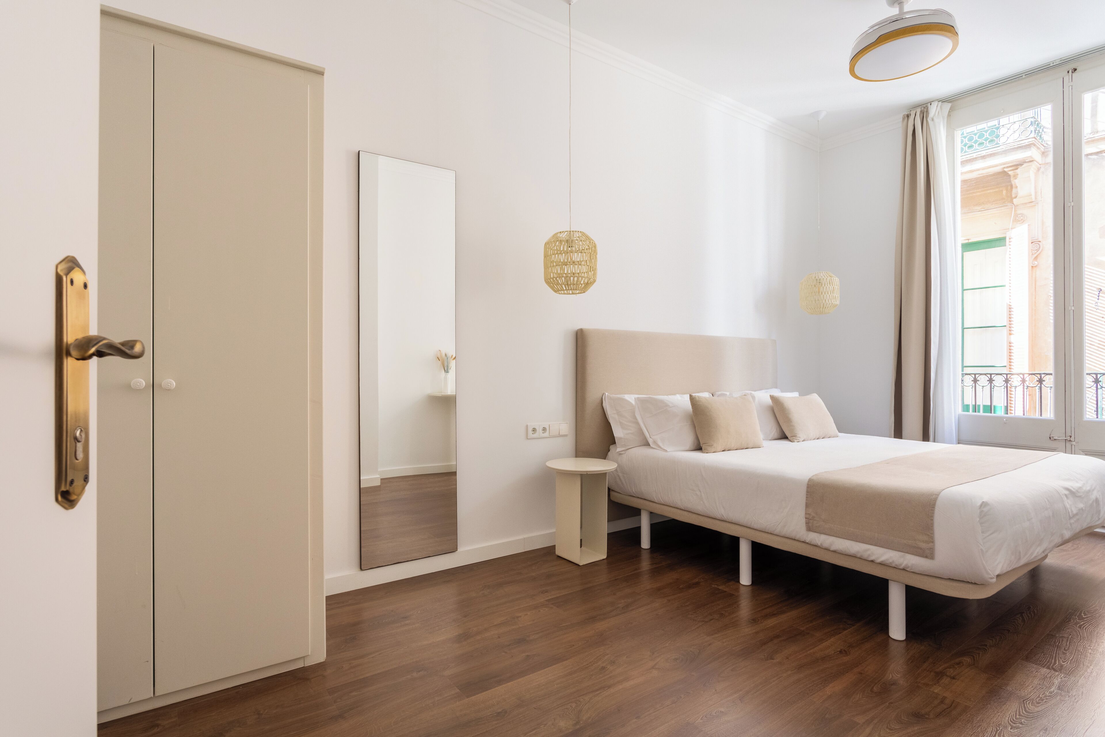 A bedroom with a bed, a wardrobe, a mirror, and a small bedside table.