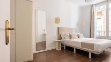 A bedroom with a bed, a wardrobe, a mirror, and a small bedside table.