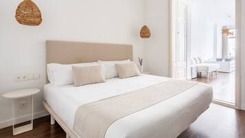 A bedroom with a large bed, bedside tables, and a view of the adjacent room.