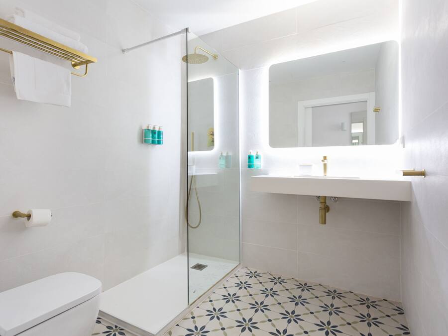 A modern bathroom with a glass-enclosed shower, white fixtures, and patterned floor tiles.