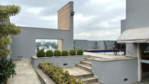 Terraza en la azotea con piscina, escalones y vista panorámica de la ciudad.