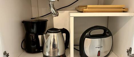 Une cuisine équipée d’une machine à café, d’une bouilloire et d’un filtre à eau Brita.