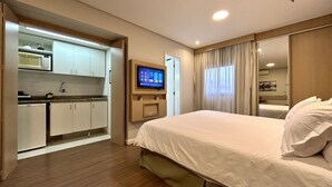 Una habitación de hotel con cama, televisión, kitchenette y baño.