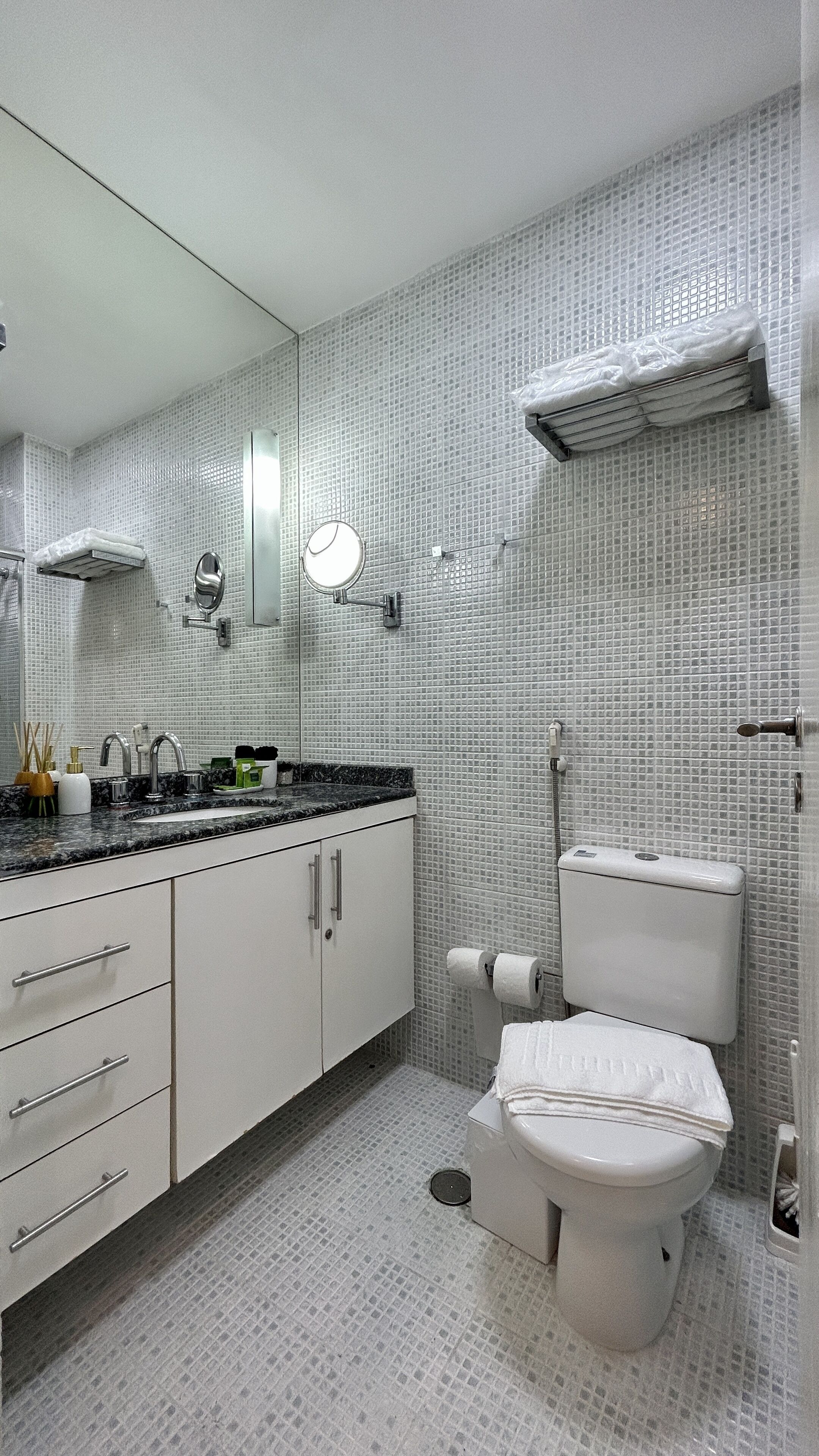 A modern bathroom with a tiled backsplash, a sink with a mirror, a toilet, and a shower area.