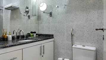 A modern bathroom with a tiled backsplash, a sink with a mirror, a toilet, and a shower area.
