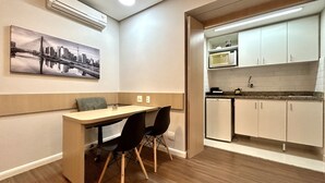Una cocina compacta equipada con microondas, fregadero y armarios. Cuenta con un comedor con mesa y sillas.