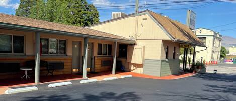 A motel with a single-story structure, a covered outdoor seating area, and a visible sign for the office.