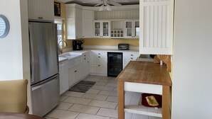 A compact kitchen with white cabinetry, a stainless steel refrigerator, a coffee maker, and a toaster. - Walk to the beach (Christiansted)