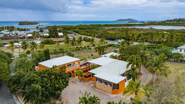A coastal property with two main buildings, a marina with boats, and a view of the ocean and hills. - Walk to the beach (Christiansted)
