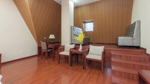 A room with wooden panel walls, a dining area with chairs and a table, and a staircase. - Yin He Hotel (Zunyi)