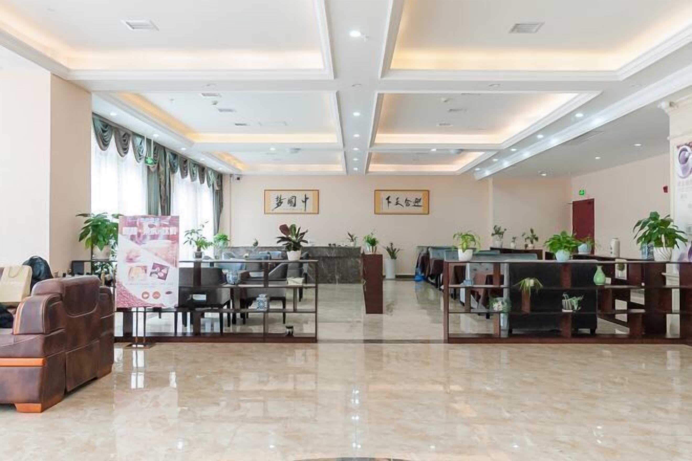 Vestíbulo de hotel con una mesa de recepción, zona de estar y plantas en macetas.