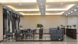 A modern lobby with a reception desk, seating area, and potted plants. - Yin He Hotel (Zunyi)