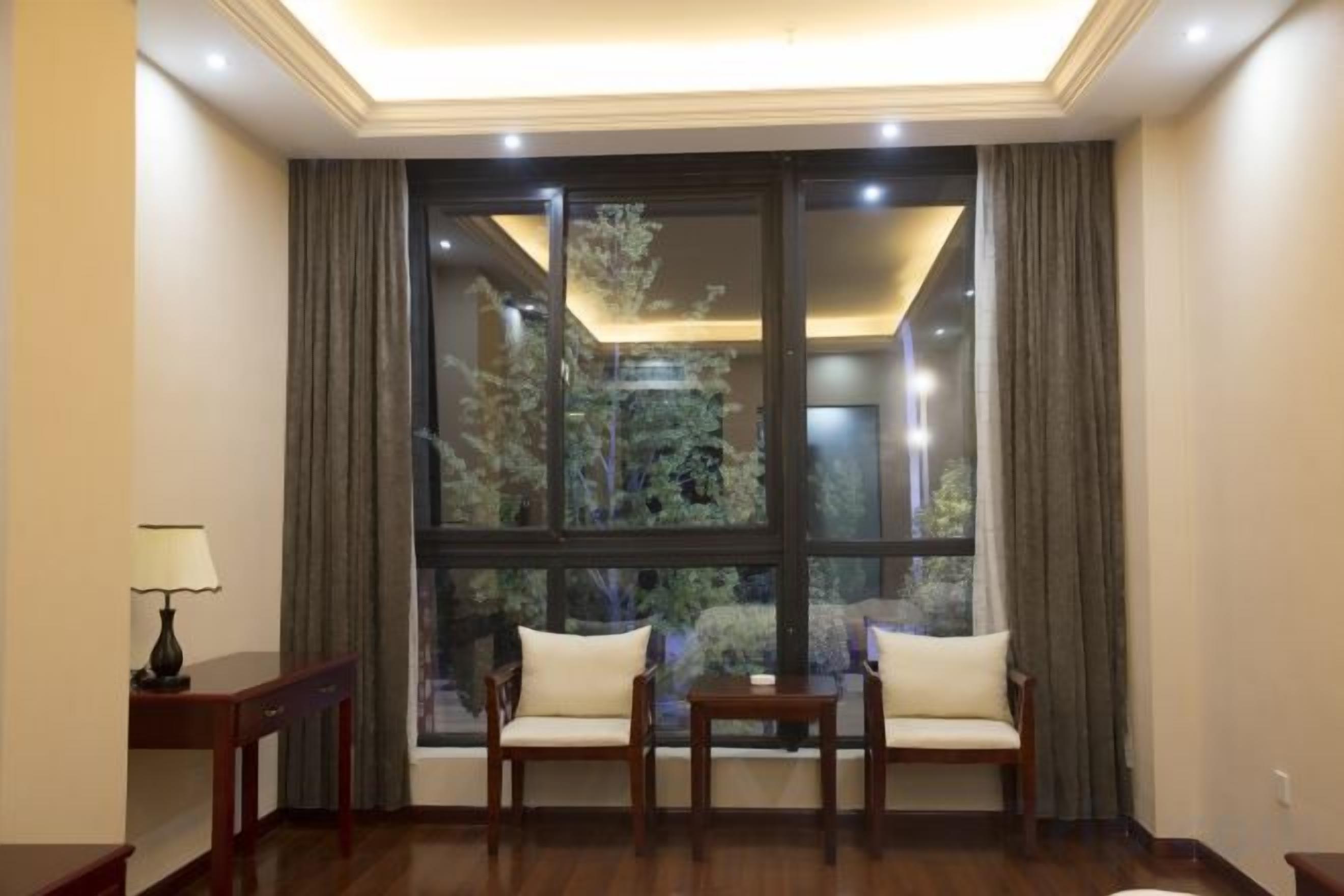 A room with a large window, two sofas, a small table, and a lamp.