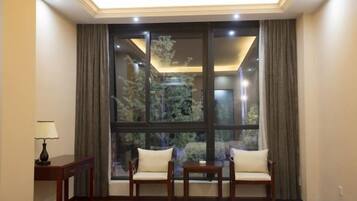 A room with a large window, two sofas, a small table, and a lamp.