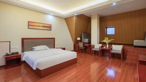 A hotel room with a large bed, a desk, a chair, a TV, and a painting on the wall. - Yin He Hotel (Zunyi)