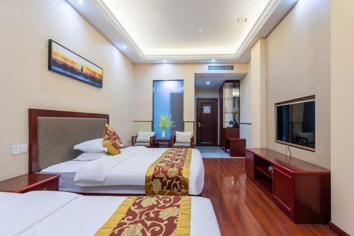 A hotel room with two beds, a TV, a desk, and a mirror.