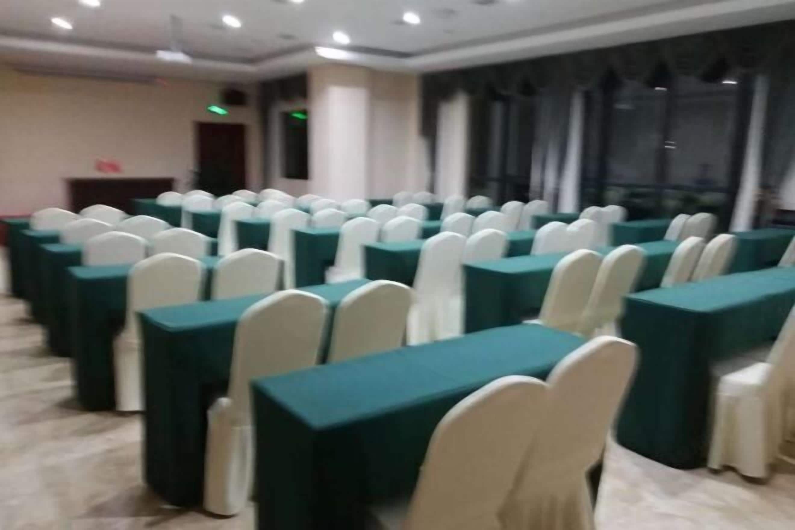 A conference room with rows of tables and chairs, large windows, and a podium.