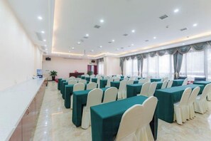 A conference room with rows of tables and chairs, a podium, and a large window with curtains. - Yin He Hotel (Zunyi)