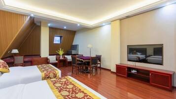A hotel room with two beds, a desk, a chair, a TV, and a staircase.