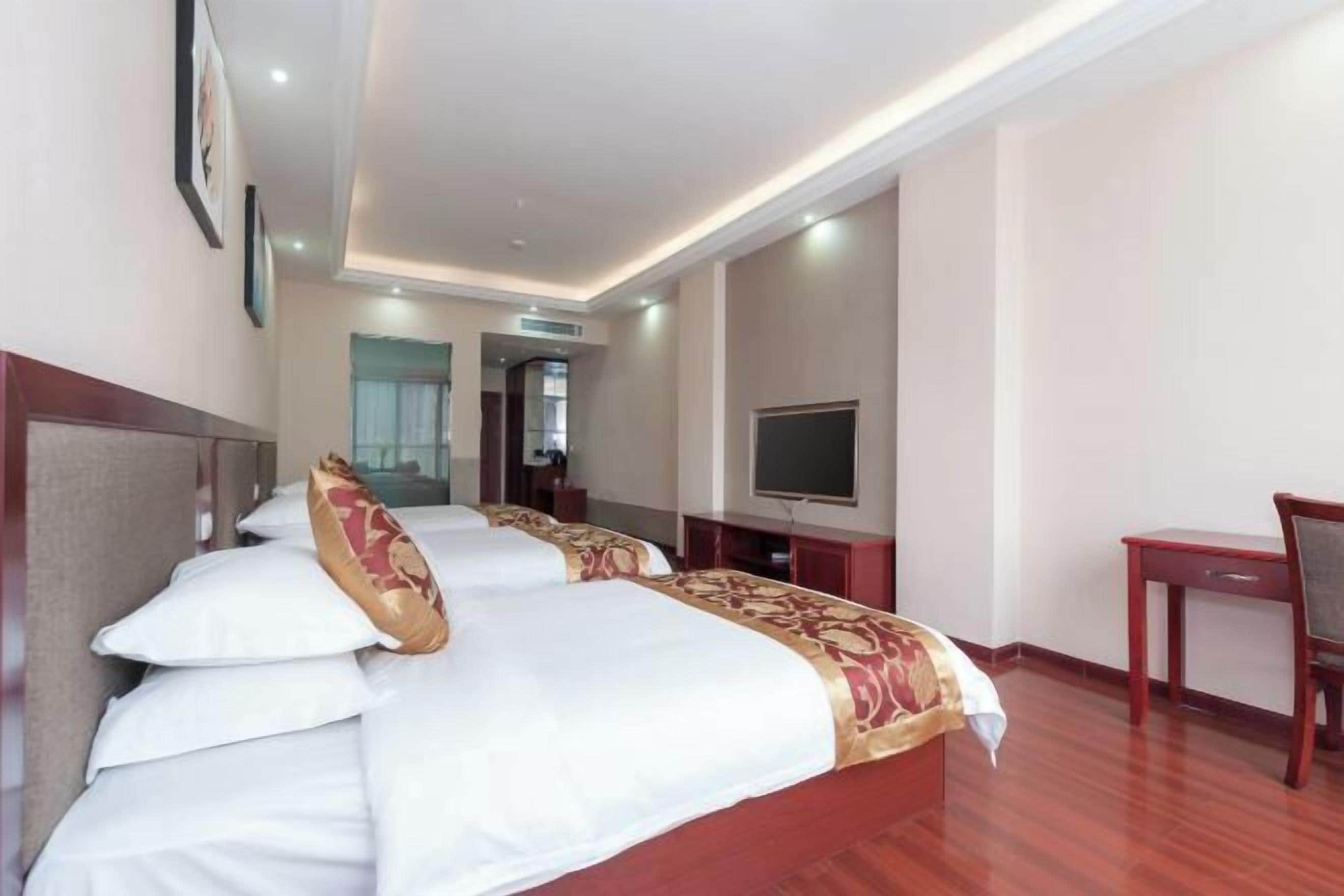 A hotel room with a large bed, a television, a desk, and a chair.