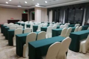 A conference room with rows of tables and chairs, a podium, and a large window. - Yin He Hotel (Zunyi)