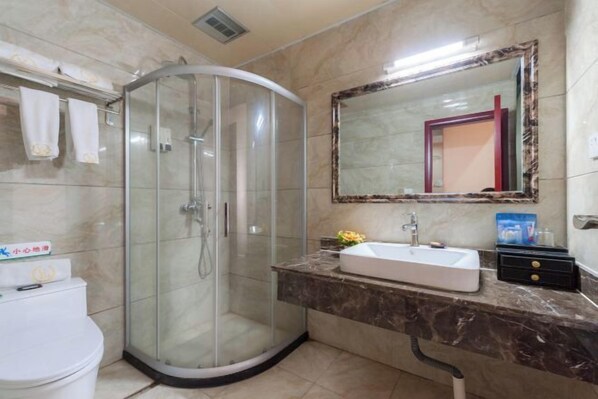 Un baño con ducha de vidrio, lavabo con encimera de mármol y espejo con marco decorativo.
