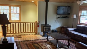 A cozy living room with wooden flooring, a sofa, a coffee table, a fireplace, and a television mounted on the wall. - Beautiful 2 bedroom house  with a boat dock on the Chippewa Flowage  (Hayward)