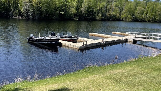 A calm lake with docked boats and a grassy shoreline. - Beautiful 2 bedroom house  with a boat dock on the Chippewa Flowage  (Hayward)