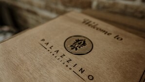 Une boîte en bois portant l’inscription « Bienvenue à PALAZZINO VENETO » et un logo.