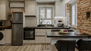 Une cuisine moderne dotée d’un îlot central, d’appareils électroménagers en acier inoxydable et d’un mur en briques.