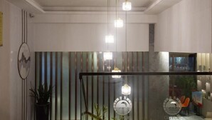 A modern interior with a glass partition, pendant lights, and a potted plant. - Guyue Hotel (Shengzhou Wuyue Plaza Branch) (Shengzhou)