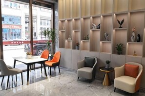 A modern interior with a seating area, a table, and shelves with decorative items. - Guyue Hotel (Shengzhou Wuyue Plaza Branch) (Shengzhou)