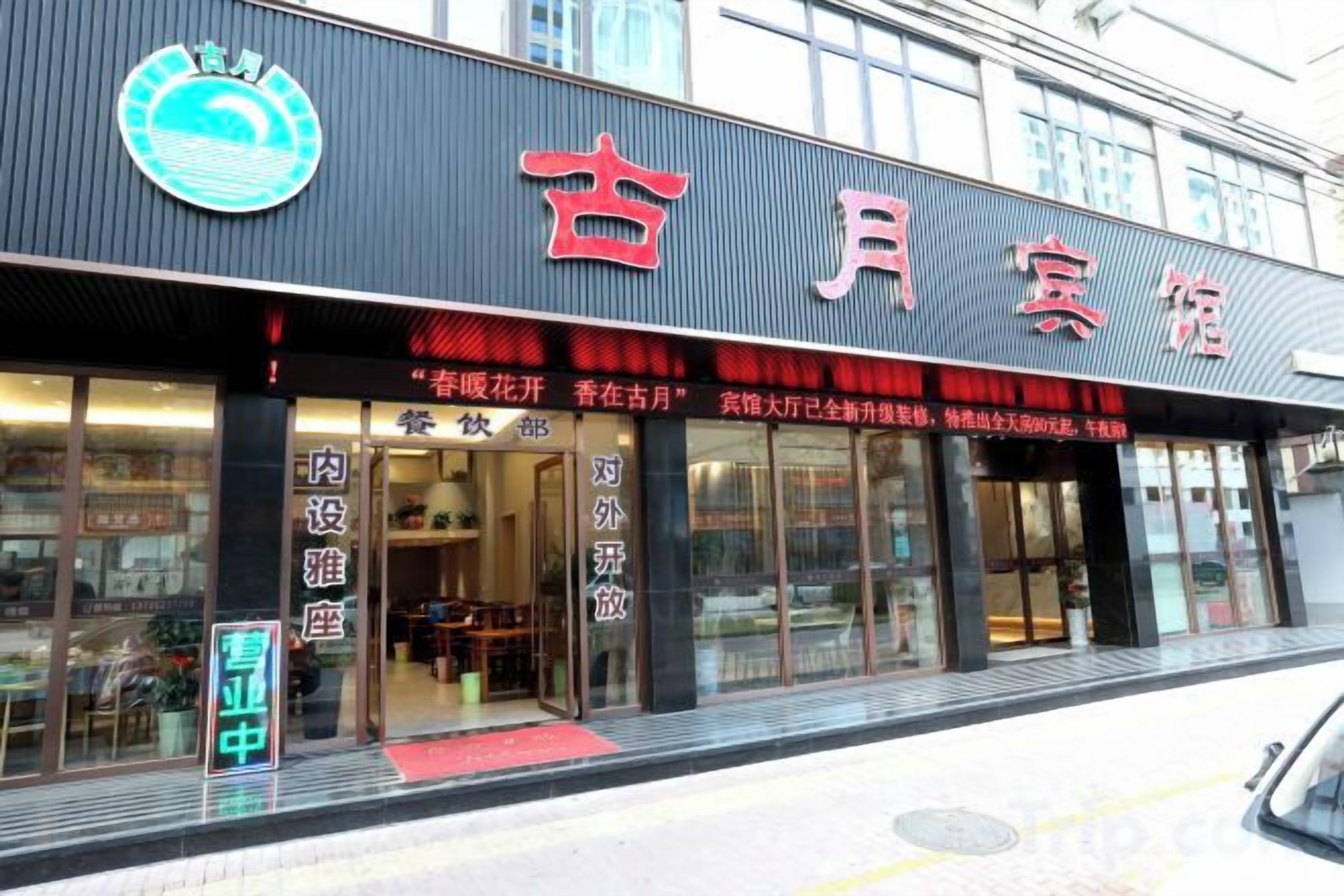 A building with a sign that reads '古月宾馆' and a logo above it.
