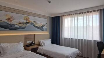 Habitación de hotel con dos camas, un cuadro en la pared, una mesita de noche, un escritorio y una ventana con cortinas.