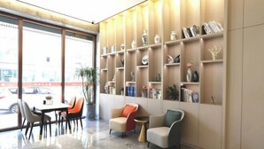 A modern lobby with a marble floor, seating area with chairs and sofas, and a bookshelf with decorative items. - Guyue Hotel (Shengzhou Wuyue Plaza Branch) (Shengzhou)