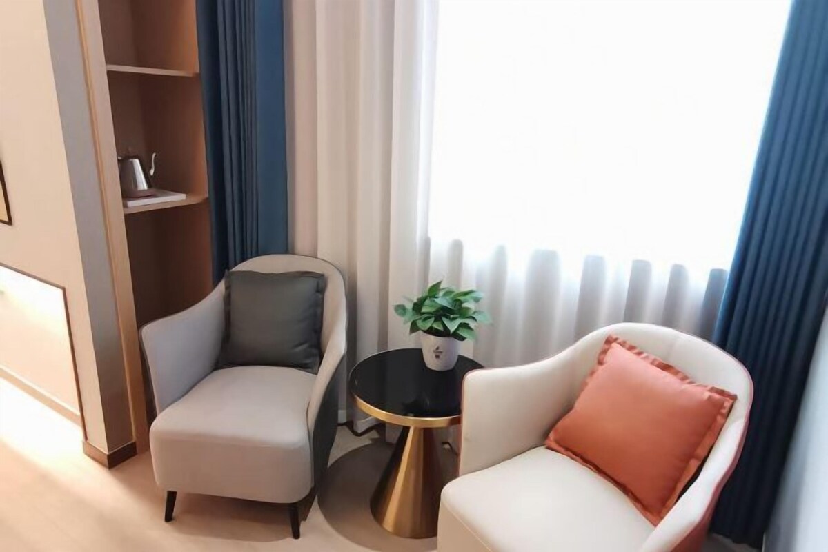 A modern room with two armchairs, a small round table with a plant, and a radiator.