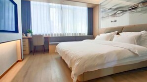 A modern hotel room with a large bed, a desk, and a window with curtains. - Guyue Hotel (Shengzhou Wuyue Plaza Branch) (Shengzhou)