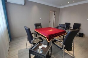 A conference room with a red table, six chairs, a small table with a bowl and napkin, and a door in the background. - Guyue Hotel (Shengzhou Wuyue Plaza Branch) (Shengzhou)