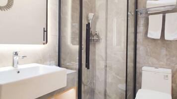 Un baño moderno con ducha de vidrio, lavamanos blanco y retrete.
